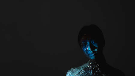 Art portrait. Female loneliness. Melancholic sadness. Quiet depression. Blue color Asian woman face silhouette with abstract water drop pattern light isolated on black night copy space background.の写真素材