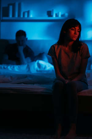 Couple argument. Night fight. Divorce breakup. Dissatisfied sad pensive woman sitting on bed on...