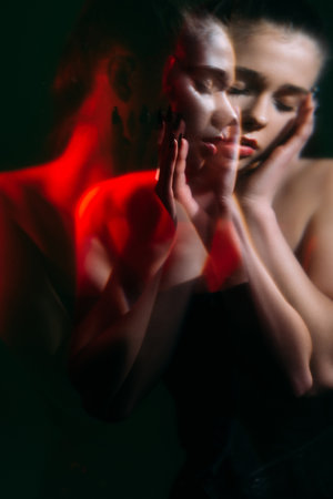 Female crisis. Mental disorder. Loneliness pressure. Double exposure blur silhouette night portrait of hurt woman with closed eyes in pain in red neon light isolated on dark green aged background.の写真素材