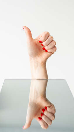 Female uncertainty. Doubt disagreement. Compromise choice. Woman hand with red nails showing thumb...