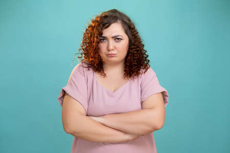 Sad woman. Body shaming. Diet problem. Overweight struggle. Conceptual portrait. Offended plus size lady looking at camera almost crying isolated blue.の写真素材