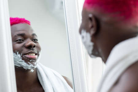 Morning grooming. Happy black man. Shaving procedure. Facial care. Reflection smiling metrosexual...