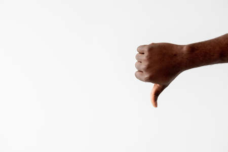 Dislike gesture. Black lives matter. Wrong choice. Failure mistake. Unrecognizable african male hand showing thumb down isolated white copy space. Advertising background.の写真素材