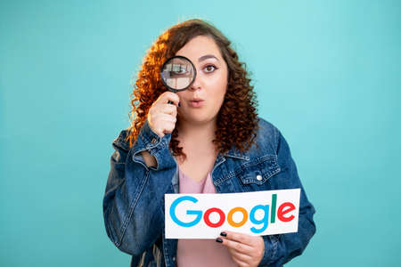 Kharkiv, Ukraine - November 06, 2020: Google search. Internet browser. Information investigation. Web page. Surprised woman looking through loupe holding note with symbol icon isolated blue.のeditorial素材