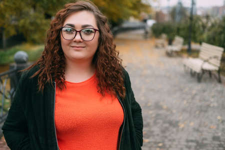 Enjoying walk. Happy plus size woman. Body positive. Healthy lifestyle. Smiling fatty lady in sportive clothes spectacles on street alley autumn season copy space.の写真素材