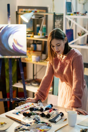 Painter lifestyle. Professional art. Creative skill. Pensive female artist standing at workplace...