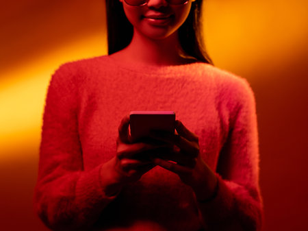 Cyberpunk people. Spiritual portrait. Future faith. Blue neon light art portrait of Asian prayer girl in black leather jacket namaste with white halo in red color smoke on dark.の写真素材