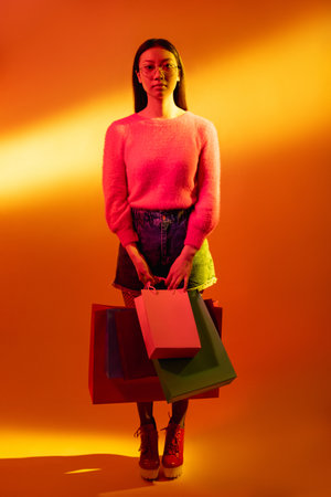 Cyberpunk people. Spiritual portrait. Future faith. Blue neon light art portrait of Asian prayer girl in black leather jacket namaste with white halo in red color smoke on dark.の写真素材