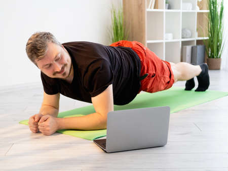 Fitness video training. Sportive man. Home gym. Healthy body. Static workout. Smiling guy in t-shirt...