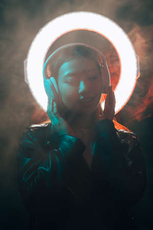 Cyber music. Dark neon portrait. Digital technology. Blue red neon light relaxed Asian girl with...
