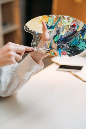 Art tools. Female painter. Mixing colors. Painting school. Unrecognizable woman holding palette with...