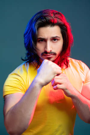 Macho strong man. Masculine power. Fashion portrait. Neon light people. Confident guy yellow t-shirt...