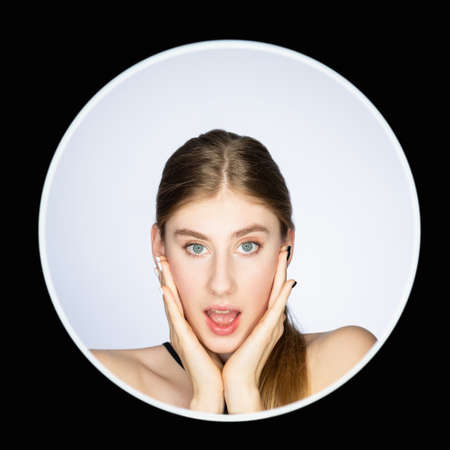 Surprising news. Wow reaction. Special offer. Headshot portrait of impressed woman face with open mouth isolated on light background in round avatar frame on black.の写真素材