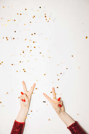 Cool party. Festive background. Holiday celebration. Female hands red dress showing peace gesture...