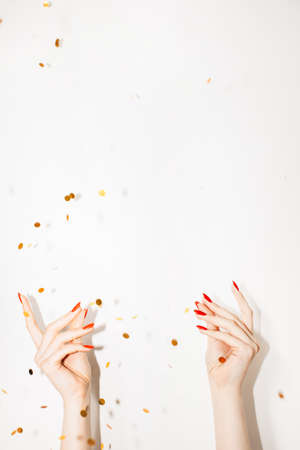 Party decor. Festive invitation. Holiday celebration. Advertising background. Elegant female hands clapping fingers showing copy space with golden confetti spangles on white.の写真素材