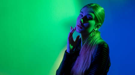 Color light portrait. Neon beauty. Futuristic fashion. Green blue glow pretty woman in black leather...