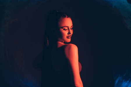 Gothic woman. Silhouette portrait. Witch magic. Feminine nature. Smiling seductive lady posing on dark circle cave blue red neon light shadow.の写真素材