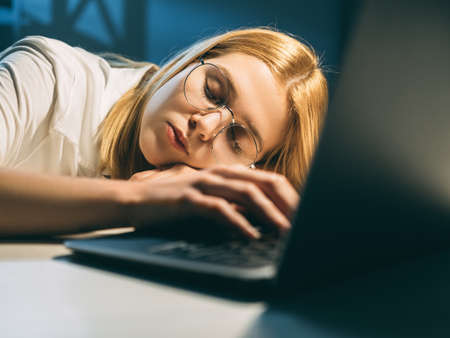 Night study. Working fatigue. Peaceful exhausted tired female student in eyeglasses sleeping with...