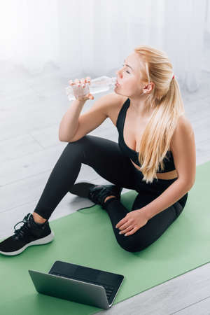 Exhausted training. Thirsty woman. Home sport. REfreshing body. Athletic lady in black sportswear...