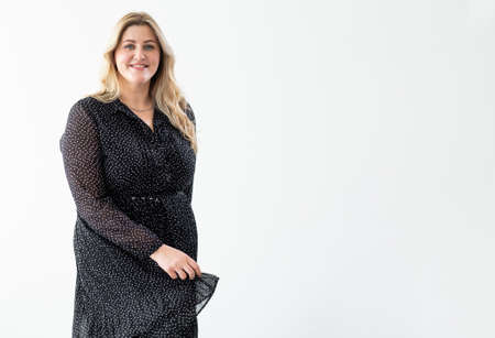 Overweight beauty. Body positive. Plus size clothing. Obesity self-acceptance. Confident happy carefree smiling curvy woman in elegant black dress isolated on white copy space background.の写真素材