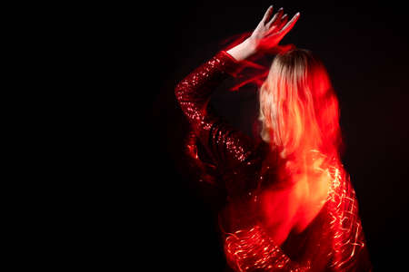Spiritual energy. Magic woman. Holiday dance. Party courage. Elegant sensual lady bare back dress moving long exposure defocused red light isolated black copy space.の写真素材