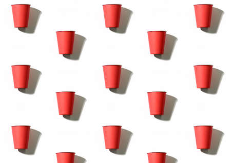 Utensils background. Cups pattern. Picnic leisure. Coffee to go. Collection of red symmetrical reusable paper mugs isolated on white surface.の写真素材