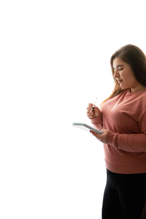 Diet planning. Weight loss strategy. Information manage. Body positive. Focused pensive obese overweight woman taking notes isolated on white empty space background.の写真素材
