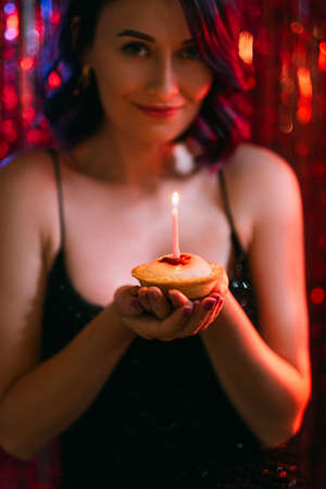 Birthday cake. Happy woman. Holiday celebration. Pretty smiling lady elegant dress making wish with...