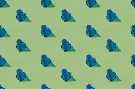 Utensil cup pattern. Abstract background. Lunch tableware. Plastic littering. Collection of blue minimalist symmetrical reusable empty glasses isolated on olive surface.の写真素材