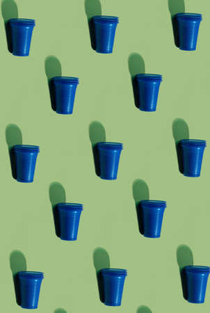 Cup serving pattern. Tableware background. Picnic utensils. Plastic reclamation. Set of blue abstract disposable empty glasses isolated on olive green surface.の写真素材