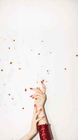 Christmas background. Festive decor. Holiday party. Happy celebration. Elegant female hands holding together showing on copy space with golden confetti spangles isolated white.の写真素材