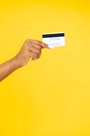 Banking service. Money transfer. Online shopping. Closeup of black woman hand holding credit card isolated on orange copy space background.の写真素材