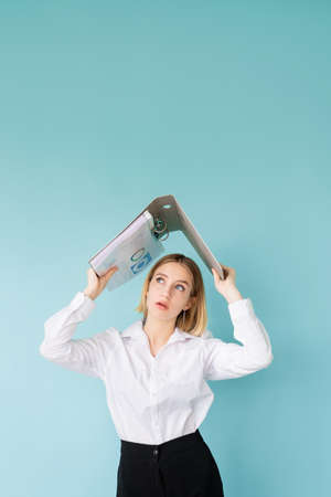 Project fail. Shocked woman. Hiding problem. Bad news. Stunning business lady covering head with folder like roof isolated blue.の写真素材