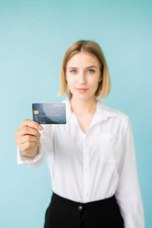 Bank credit. Female officer. Loan rate. Online payments. Best proposition. Happy official woman holding plastic card in hand isolated blue.の写真素材