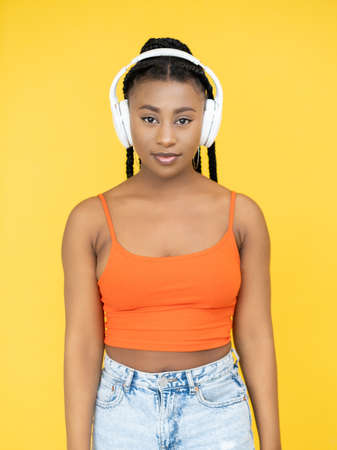 Music device. Audio track. Stereo sound. Millennial Afro woman in earphones listening song playlist isolated on orange background.の写真素材
