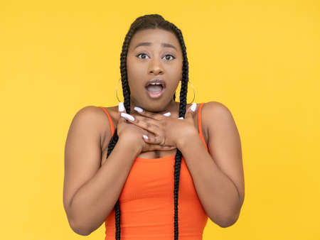 Omg face. Shock expression. Unexpected surprise. Amazed astonished African woman with open mouth in gasp isolated on yellow background.の写真素材