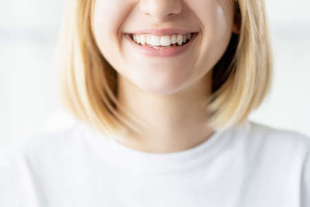 Healthy smile. Dental care. Stomatology treatment. Unrecognizable woman face closeup with perfect white teeth isolated on light background.の写真素材
