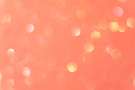 Bokeh light overlay. Glowing circles. Festive sparks. Flash effect filter. Defocused pastel yellow pink round flecks on peach orange abstract background.の写真素材