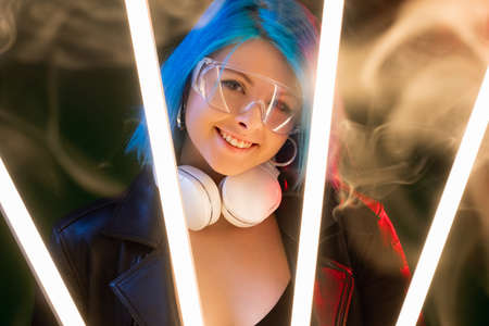 Cyberpunk woman. Sci-fi style. Futuristic subculture. Attractive happy smiling model in earphones in...