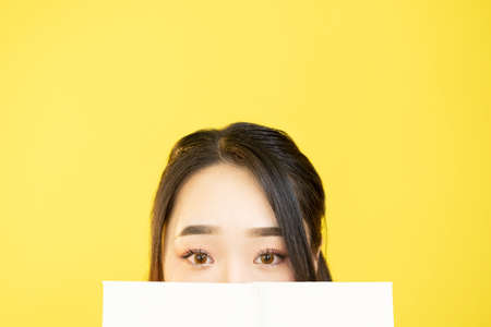 Student portrait. Hiding woman. School education. Exam study. Cute curious teen girl face behind...