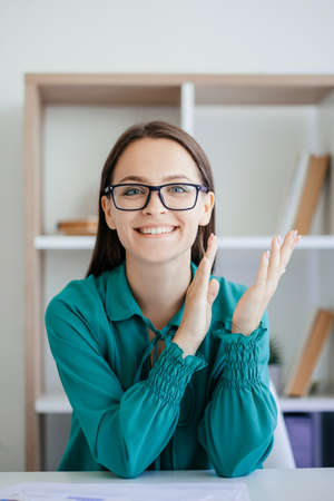Successful project. Corporate congratulation. Job promotion. Satisfied proud cheerful business woman in glasses applauding smiling at office workplace.の写真素材