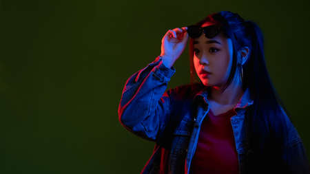 Curious woman. Offer banner. Interested expression. Neon light people. Pretty cyberpunk model in multicolor red glow isolated on black empty space background.の写真素材