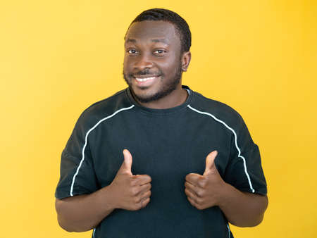 Good choice. Supportive man. Approve sign. Happy guy in sportive t-shirt showing like gesture thumbs up isolated yellow.の写真素材