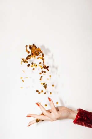 Festive background. Womans day party. Greeting card. Elegant female hand red dress throwing golden glitter spangles confetti isolated white copy space.の写真素材