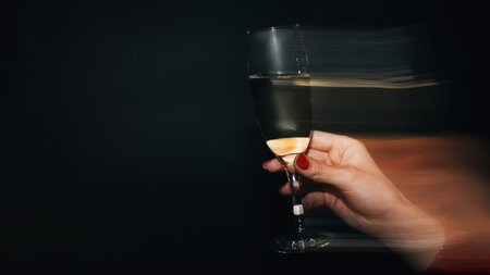Party spirit. Happy womans day. Funny holiday. Festive celebration. Female hand holding glass of champagne long exposure defocused light isolated black copy space.の写真素材