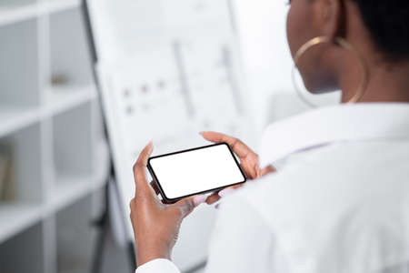 Mobile app. Gadget leisure. Phone advertisement. Touchscreen template. Unrecognizable woman using cell white copy space screen mockup indoors.の写真素材