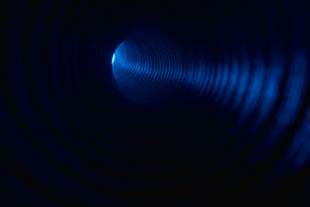 Fluorescent background. Blur neon light. Spotlight illumination. Defocused led blue color glow ray in ribbed texture swirl tunnel on dark black copy space.の写真素材