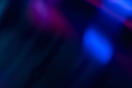 Defocused glow overlay. Bokeh neon light. UV led glare. Blur fluorescent purple blue color flecks rays pattern on dark black abstract background.の写真素材