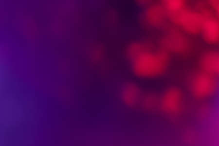 Bokeh light background. Blur sparks. Fluorescent fantasy glare. Defocused neon red purple color glow round flecks pattern on vibrant abstract overlay.の写真素材