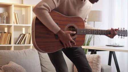 Guitar leisure. Music hobby. Quarantine activity. Joyful talented young man guitarist playing song...